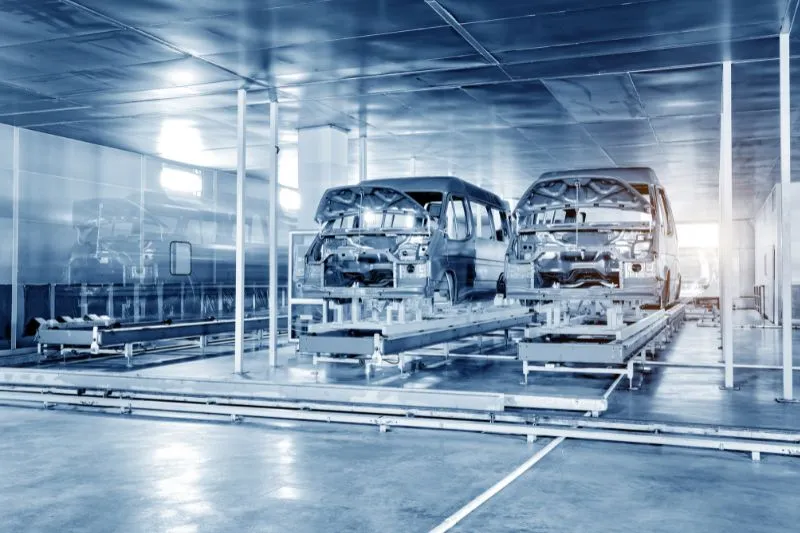 Two unfinished vehicles on an assembly line in an automobile factory, representing the use of 2D animated explainer videos by a top animation agency to showcase advanced features and safety technologies of a new car model, increasing customer interest and test drive requests.