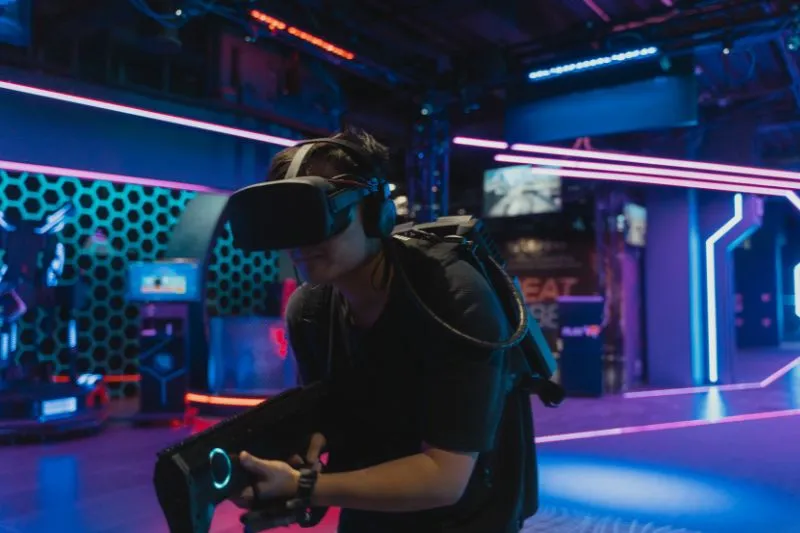 A person wearing a VR headset and holding a gaming controller in a futuristic gaming environment, demonstrating the use of 3D animation services to create lifelike characters and realistic settings for enhanced storytelling in video games.